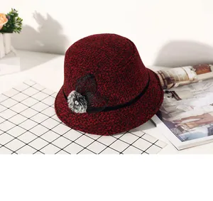 Detail of red tweed winter hat featuring a mesh bow, faux fur pompom and rhinestone