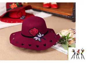 Detail of red wool felt hat featuring rose embroidery and heart cutout brim design