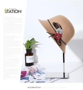Detail of camel wool cloche hat with 3D flower decor and polka dot ribbon on a silver stand