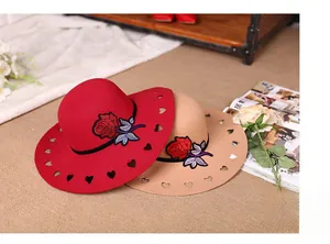 Detail of red and beige wide-brim wool felt hats with rose embroidery and heart cut-outs