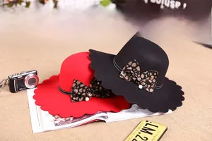 Detail of wool fedora with wavy scalloped brim featuring leopard bow and pearl charm