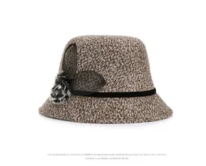 Detail of tweed winter hat with mesh flower, fur pom-pom, and rhinestone accents