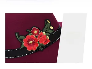 Detail of red wool felt hat with floral embroidery and decorative black ribbon