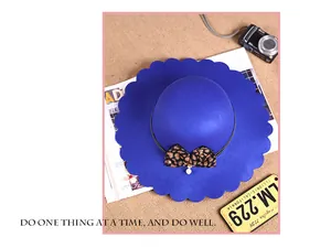 Detail of scalloped edge blue wool hat with leopard print bow and pearl accent
