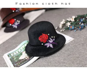 Close-up of black faux mink fur hat with red rose embroidery and sparkling rhinestones