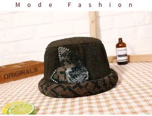 Close-up of brown knit bucket hat with F-pattern brim, rhinestone ears and fur pom-pom