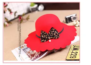 Detail of red wool felt hat with wavy brim, leopard bow, and pearl ornament