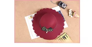 Detail of scalloped edge wine red wool fedora with leopard bow and pearl charm