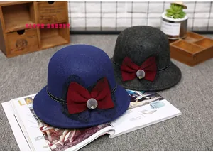 Detail of wool bowler hats with oversized burgundy bows and decorative fur pom-poms