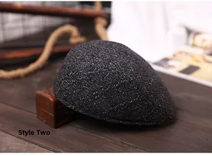 Close-up of Style 2 grey herringbone tweed flat cap on a rustic wooden table