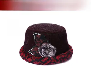 Close-up of wine red winter bucket hat with floral detail and faux fur ball for women