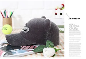 Detail of plush grey equestrian cap featuring rhinestone crown logo and animal ear accents