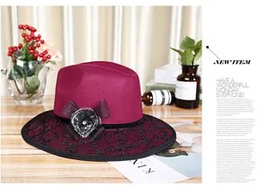 Detail of wine red wool hat with black lace, pompom, and elegant bow on wood background