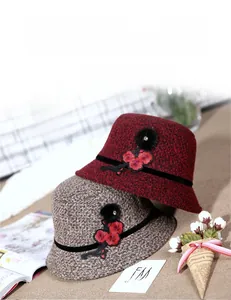 Close-up of wool cloche hats with floral embroidery and rhinestone fur ball detail