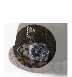 Detail of a brown leopard print winter hat with faux fur pompom and silver leaf accents