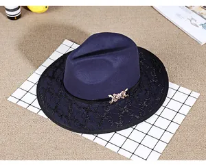 Detail of dark blue wool fedora hat featuring black lace embroidery and a gold bow buckle