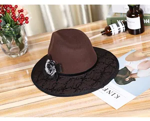 Detailed view of brown wool fedora with black lace trim and flower on wooden surface