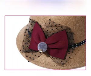 Close-up of wool fedora hat with bow, polka dot mesh, pom pom and rhinestone detail