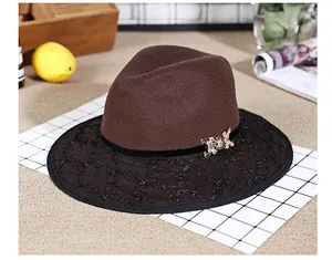 Detail of brown fedora hat featuring black lace embroidery and a gold metallic bow buckle