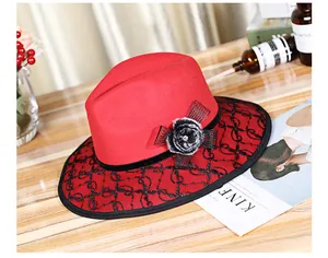 Detail of red fedora hat with black lace overlay and decorative faux fur flower accent