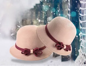 Detail of wool cloche hat in camel with a wine red bow ribbon for winter fashion