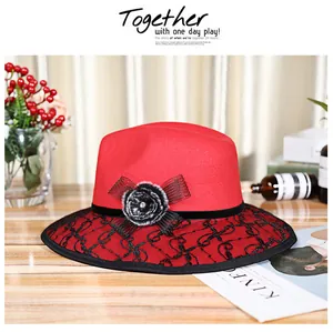 Close-up of red wool felt hat with black lace brim, bow, and faux fur flower detail