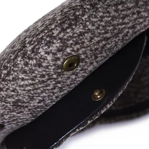 Macro detail of tweed fabric texture and bronze snap button on a men's flat cap