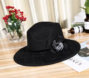 Detail of black wool fedora featuring lace embroidery brim and soft pom-pom accent