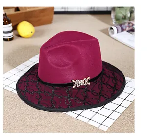Detail of burgundy fedora hat with black lace overlay and golden bow buckle decoration