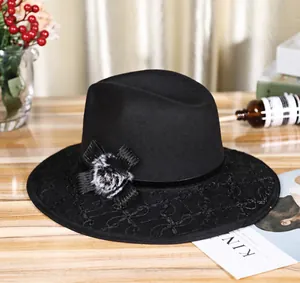 Detail of black wool fedora hat featuring delicate lace brim and faux fur pompom accents