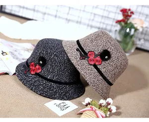 Detailed close-up of thick tweed winter hats with floral embroidery and plush fur balls