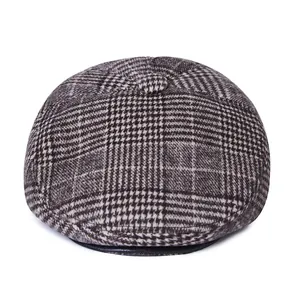 Detailed view of gray-brown plaid flat cap with leather brim edge and fabric texture