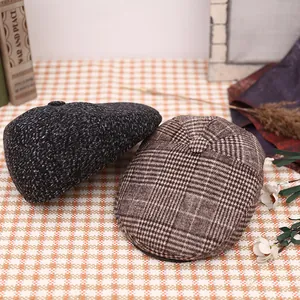 Flat lay of retro wool newsboy caps in dark grey and brown plaid on a checkered cloth