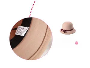 Detail of stitching and care label on beige wool hat with red ribbon for women