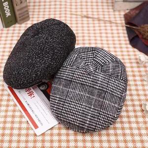 Detailed close-up of winter newsboy caps in gray wool and vintage plaid pattern fabric