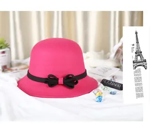 Close-up of fuchsia wool cloche hat with black ribbon and double bow on white fabric