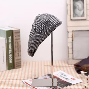 Detailed view of gray houndstooth flat cap displayed on a silver metal stand