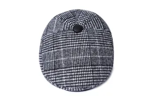 Close-up of classic grey plaid tweed flat cap with a black button top and wool texture