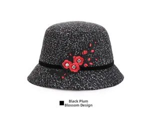 Close-up of black and white tweed bucket hat with red plum embroidery and rhinestone detail