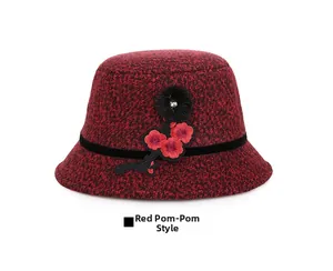 Detail of red tweed cloche hat featuring floral embroidery and a black faux fur pompom