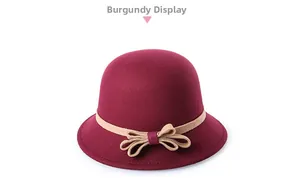 Detail of wine red wool cloche hat featuring a beige ribbon trim and decorative bow