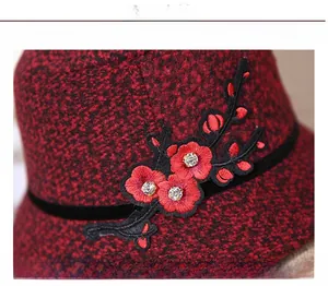 Detailed embroidery on red and black tweed hat featuring 3D floral petals and crystals