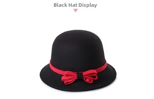 Detail of a black wool felt cloche hat featuring a vibrant red ribbon and elegant bow