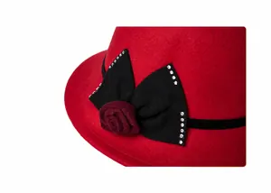 Détail d'un chapeau en laine rouge avec un nœud noir et une rose ornée de strass