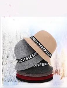 Close-up of six colorful winter felt bucket hats with LOVE ribbon decor in snow background
