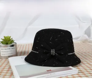 Detail of black wool bucket hat featuring rhinestone bow decoration and wavy stitching