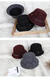 Detail of wool blend cloche hats with bow and rhinestone trim on white fur background