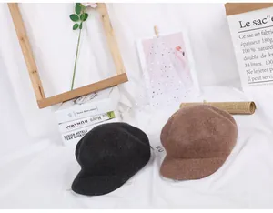 Close-up of black and brown wool newsboy hats on white cloth with vintage props