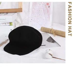 Flat lay detail of a black wool octagonal newsboy hat with stylish decorative props
