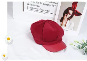 Detail of red plush octagonal hat featuring a smooth faux leather brim and retro style